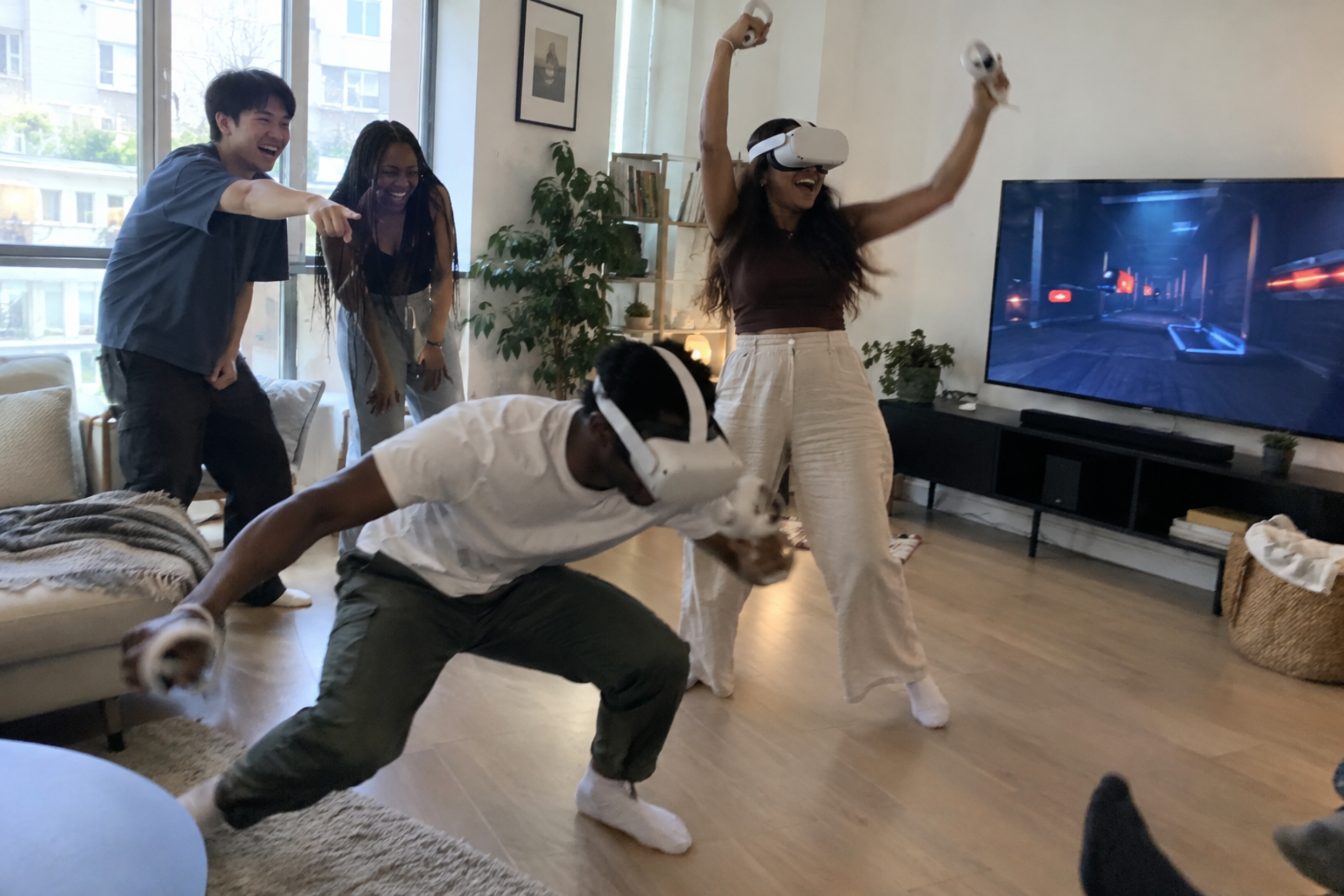 Friends laughing and celebrating as two players duck and reach in a wireless VR game